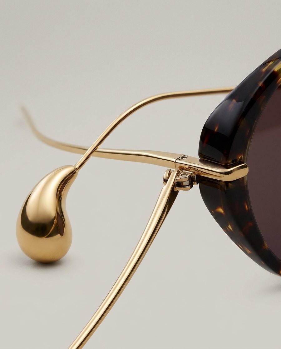 A close-up of sunglasses hardware showing three arms where the product only has two