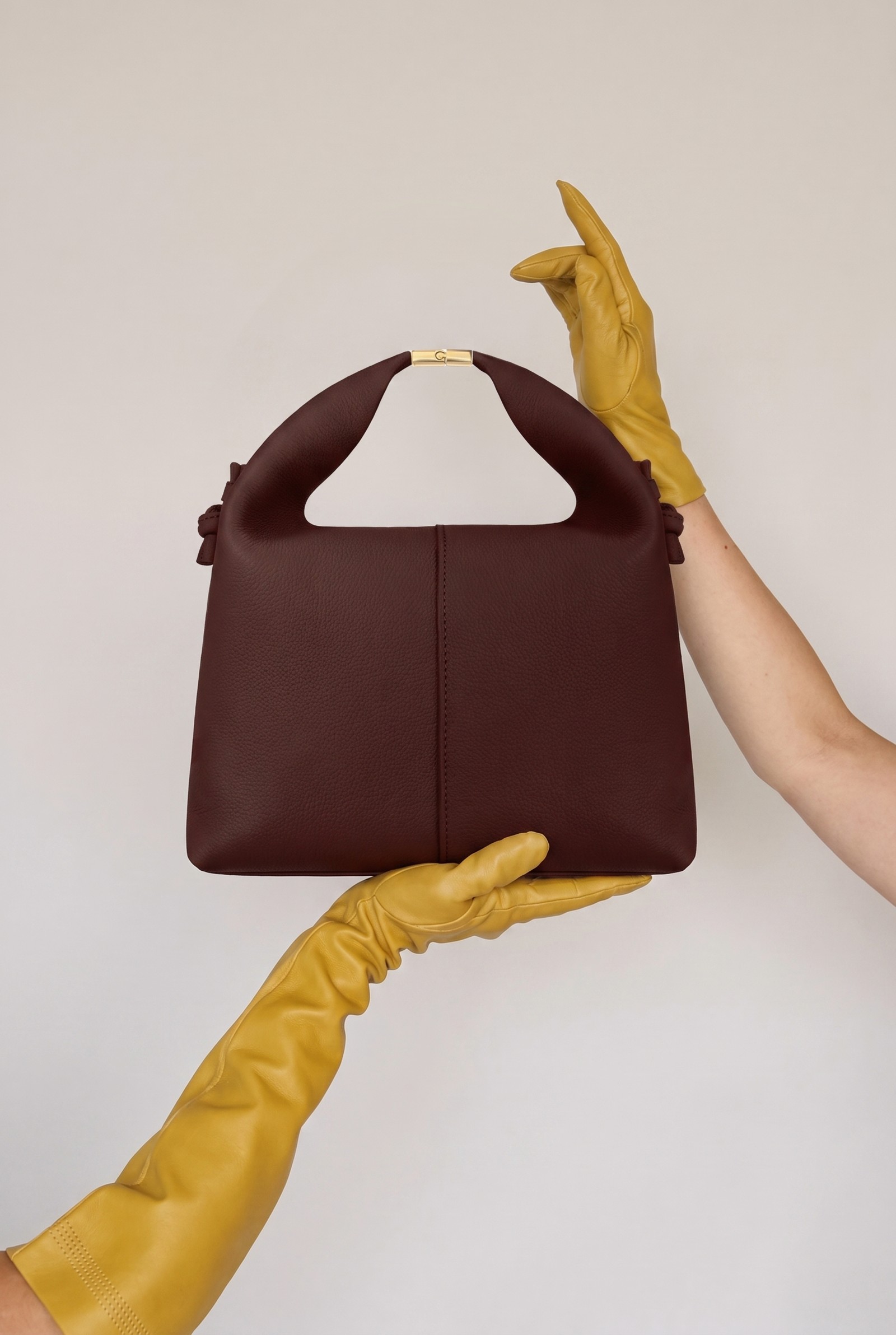 AI model shown from a different angle, front-facing bag detail with mustard-colored gloves