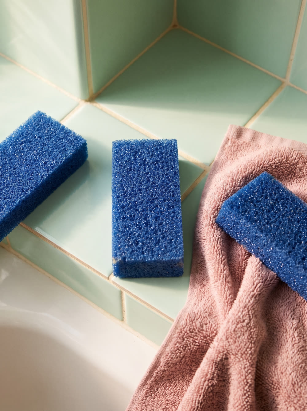 Product Shot still of three foot files styled on green bathroom tile with a pink towel