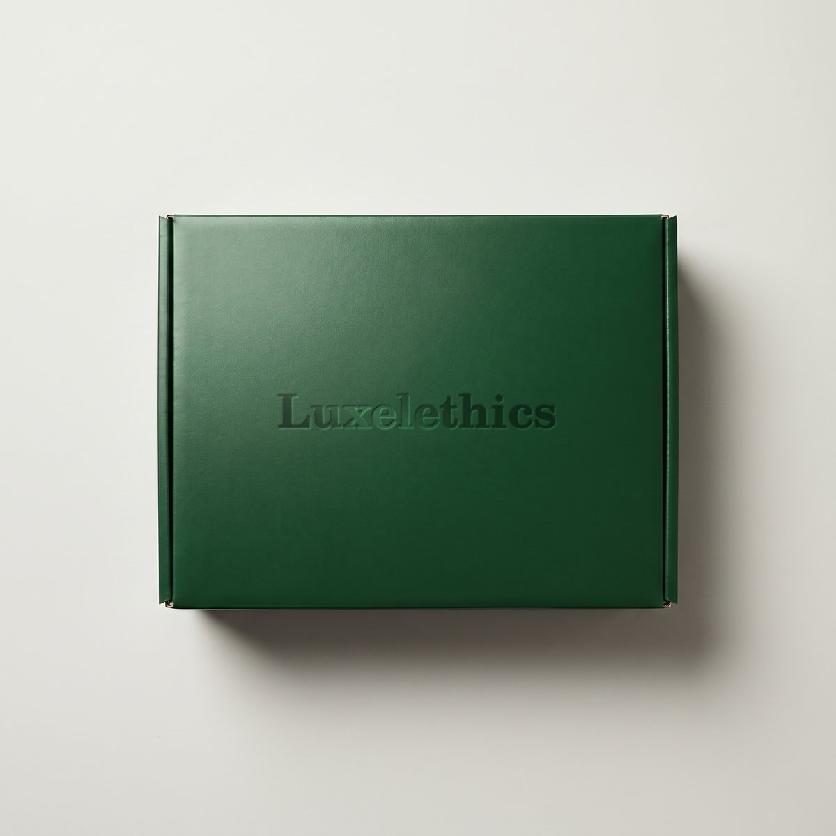 Closed rigid gift box in deep green with a debossed, high-gloss Luxelethics wordmark on the lid