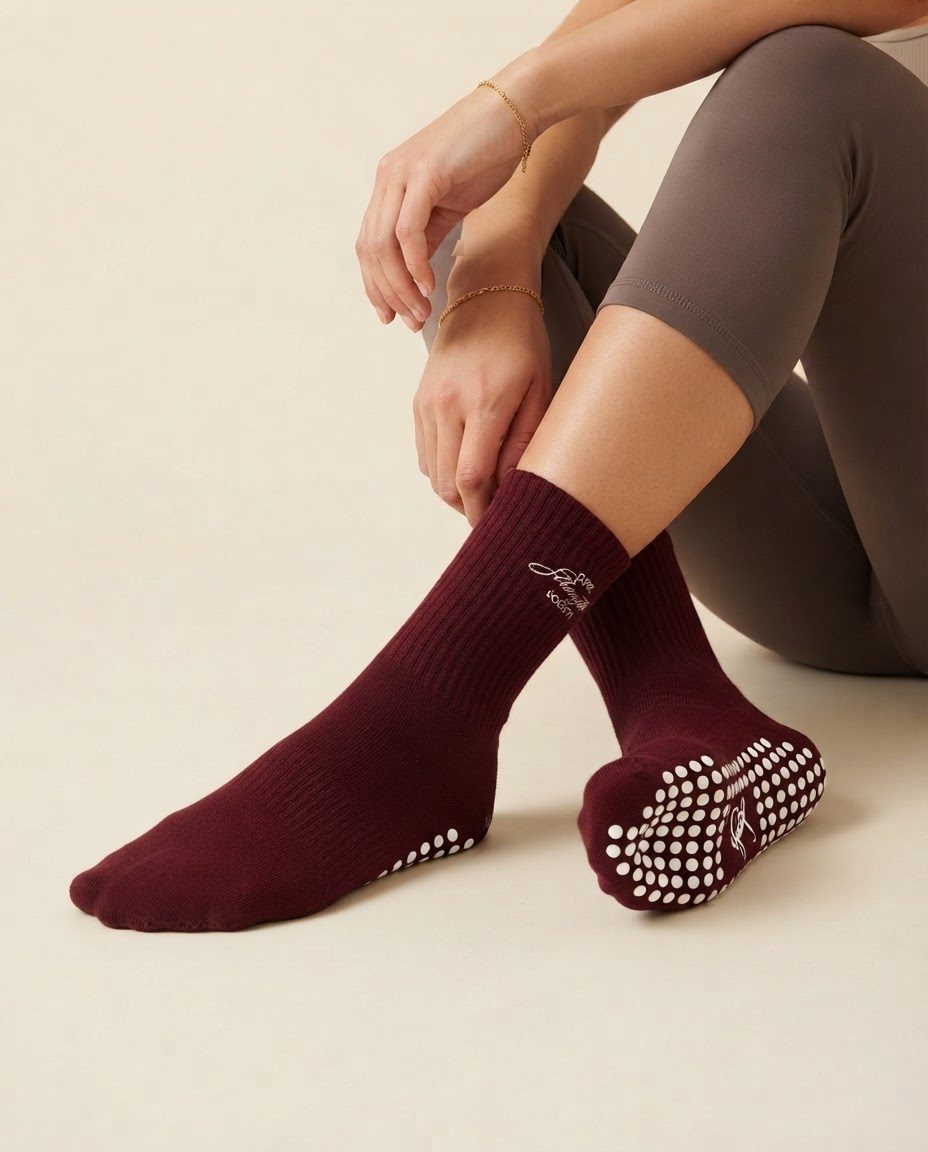 AI-generated image of a seated woman pulling up burgundy ribbed grip socks