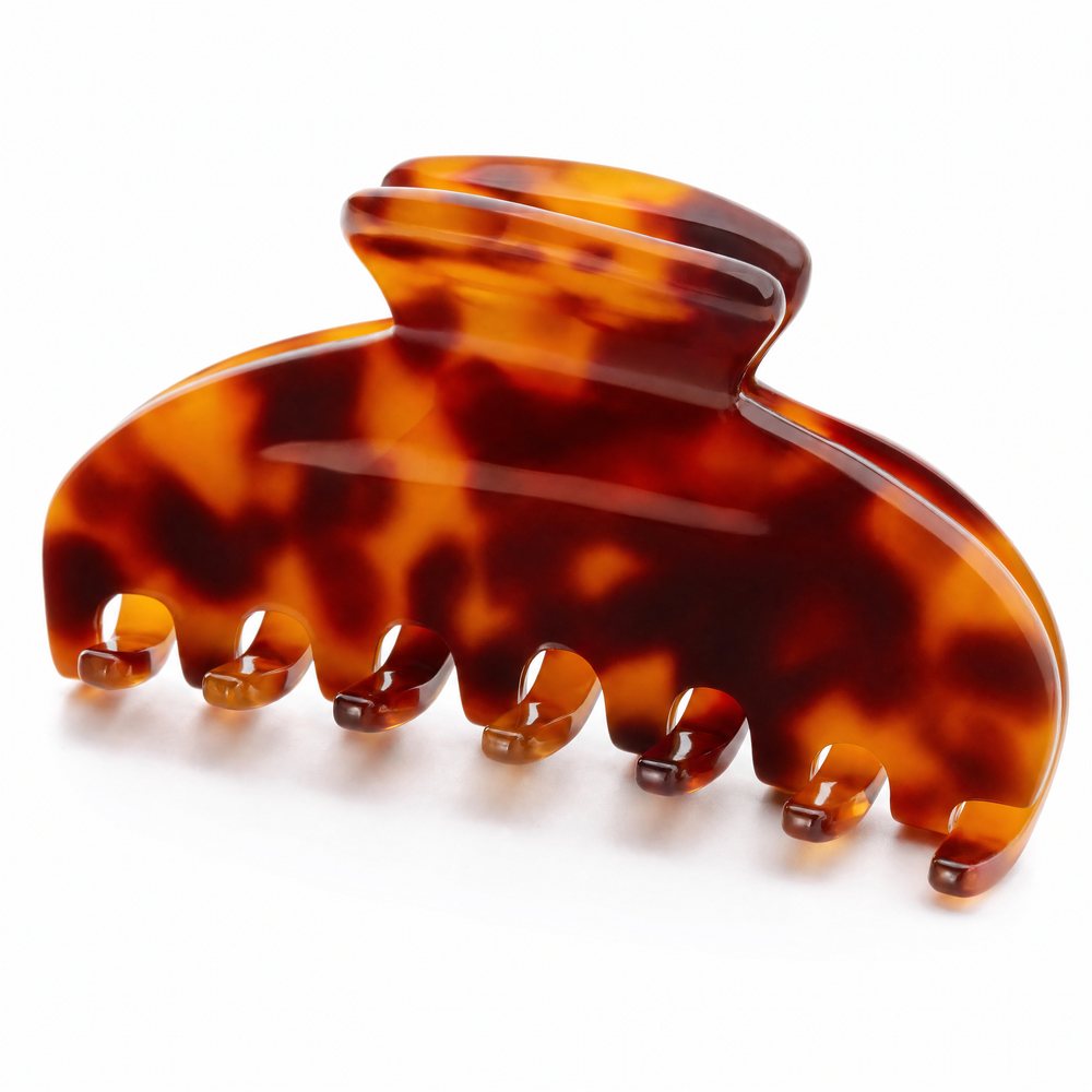 Extreme close-up of a tortoiseshell claw clip on white, showing the teeth, the hinge and the translucent amber edges
